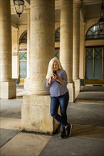 Woman using smart phone by columns of Palais-Royal in Paris, France