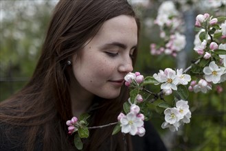 Young woman smelling white blossoms