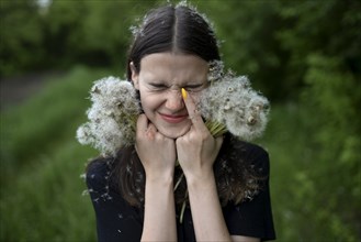 Teenage girl with her eyes closed holding dandelions