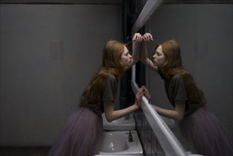 Young woman leaning on bathroom mirror