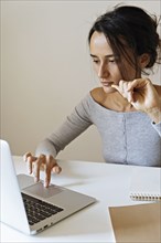 Woman using laptop with note pads