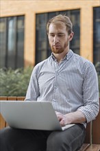 Bearded man using laptop outdoors