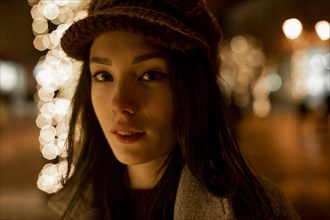 Portrait of young woman wearing woolly hat at night
