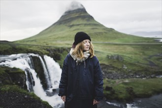 Young woman by Kirkjufell and Kirkjufellsfoss in Iceland