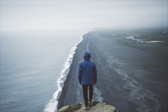 Man wearing blue coat above beach in Vik, Iceland
