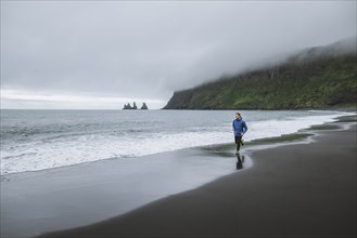 Man jogging on beach in Vik, Iceland