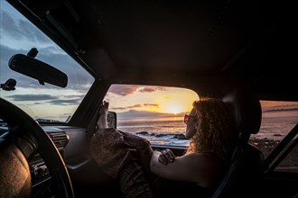 Woman in car with her legs raised watching sunset