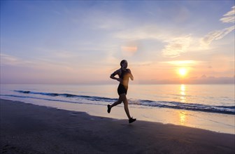 Woman jogging on beach at sunset