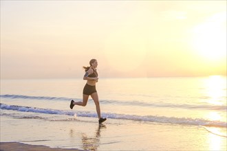 Woman jogging on beach at sunset