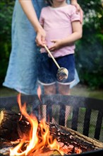 Mother and daughter toasting marshmallow over brazier