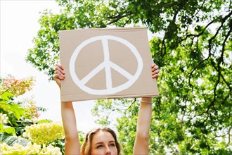 Young woman holding aloft peace symbol