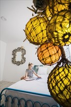 Girl reading book on bed behind decorations