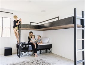 Mother reading story to children on bunk bed