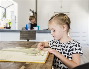 Girl reading picture book at dining table