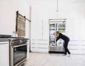 Woman reaching into refrigerator