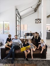 Family with book and laptop on sofa