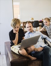 Boy using laptop on leather sofa by his family