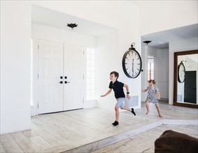 Girl chasing her brother in entrance hall
