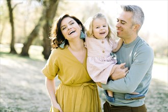 Smiling parents holding their daughter in park