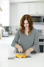 Woman slicing orange in kitchen