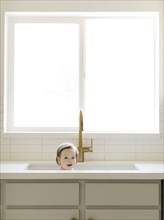 Baby girl bathing in kitchen sink