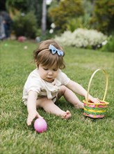 Baby girl with Easter egg and basket in back yard