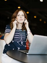 Mid adult woman using laptop and headphones