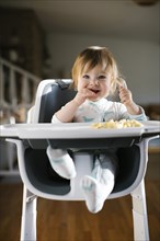 Baby girl eating in high chair