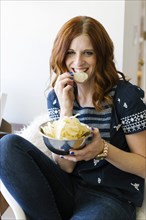 Smiling woman eating crisps from bowl