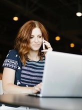 Mid adult woman using smart phone and laptop