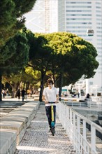 Young man using electric scooter on pavement