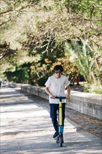 Young man using electric scooter on pavement