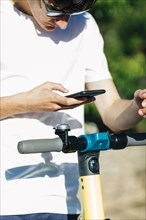 Young man using smart phone on electric scooter