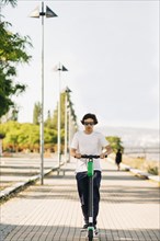 Young man using electric scooter on sidewalk