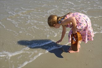 Girl bending over on beach