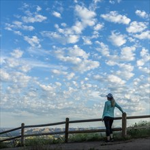 Rear view of mature woman by fence under clouds in Boise