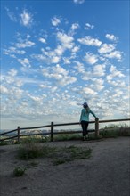 Rear view of mature woman by fence under clouds in Boise