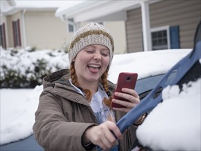 Girl taking selfie while brushing snow off of car
