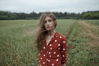 Woman wearing red polka dot shirt in wheat field