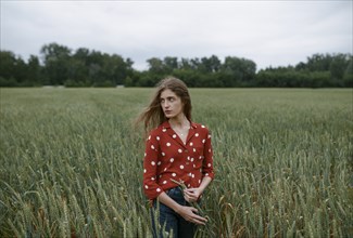 Woman wearing red polka dot shirt in wheat field