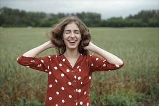 Laughing woman wearing red polka dot shirt in wheat field