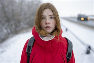 Teenage girl wearing red coat in snow