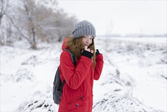 Teenage girl wearing red coat and grey hat in snow