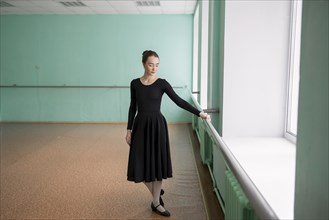 Ballet dancer wearing black dress at barre