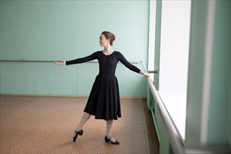 Ballet dancer wearing black dress at barre