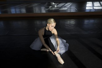 Ballet dancer adjusting leggings in studio