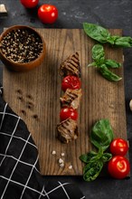 Grilled meat and tomato skewer on cutting board
