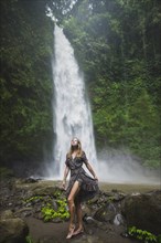 Woman standing by waterfall in Bali