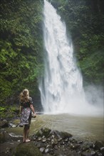 Woman standing by waterfall in Bali