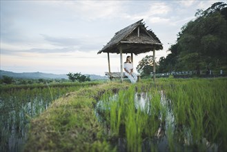 Woman sitting in hut by rice paddy in Bali